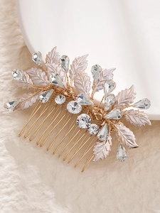 Close-up of golden bridal hair comb with rhinestone leaves and crystal detailing