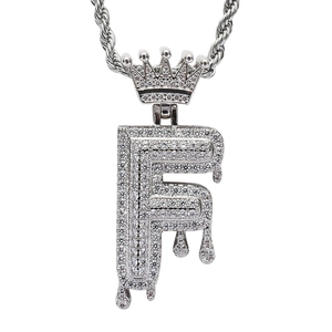 Macro detail of silver hip hop letter F pendant with crown and dripping effect zircon