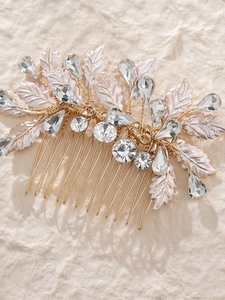 Detailed close-up of golden bridal hair comb with shimmering rhinestones and metallic leaves