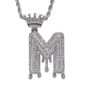 Macro detail of iced-out crown initial M pendant with dripping effect and micro pave zircons