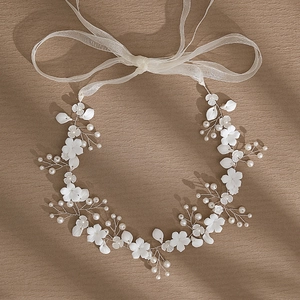 Détail de serre-tête mariage avec fleurs en porcelaine blanche, perles et ruban organza