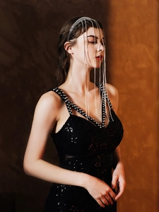 Détail d'un serre-tête à franges de cristaux scintillants et robe noire à paillettes