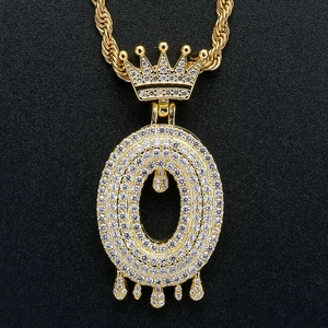 Close-up of gold iced-out crown letter pendant with rope chain on black texture