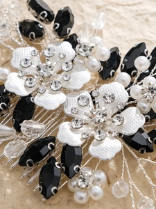 Macro detail of bridal hair comb featuring black crystals, white pearls and rhinestone flowers
