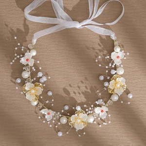 Détail du bandeau de mariée avec fleurs en résine blanche, perles et fil doré sur tissu