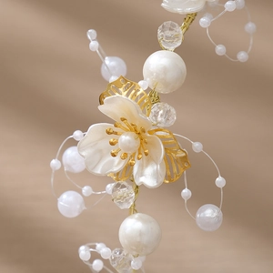 Détail du bandeau de mariée avec pétales blancs, perles et feuilles en métal doré
