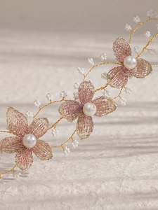 Détail d'un bandeau de mariée fait main avec fleurs en maille dorée et perles fines