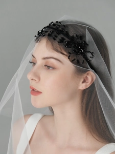 Detail of bride headband with black floral beads and white mesh veil on model