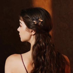Detailed view of a vintage bridal hair comb with gold metal leaves and dark crystal beads