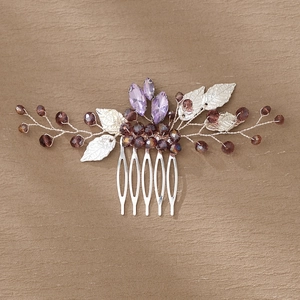 Close-up of handmade bridal hair comb with purple crystals, brown beads and silver leaves