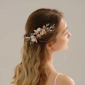 Détail d'un peigne à cheveux pour mariée avec fleurs roses, perles et feuilles d'or