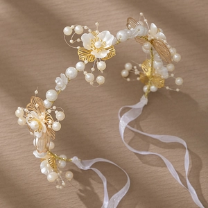Détail d'un bandeau de mariée avec perles ivoire, feuilles dorées et pétales en soie