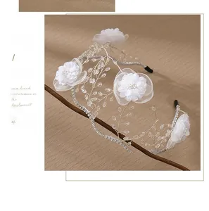 Detailed macro view of handmade bridal headband with white mesh flowers and crystal beads