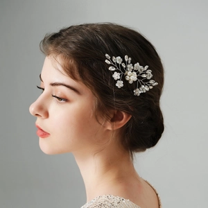 Vista dettagliata del pettine da sposa con perle e fiori bianchi indossato dalla modella