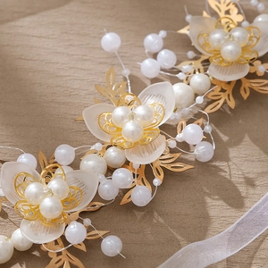 Détail d'un bandeau de mariée avec pétales de résine mate, perles et feuilles dorées