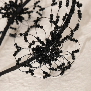 Detailed close-up of handmade black crystal beaded floral patterns on an elegant headband