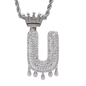 Close-up of hip hop letter U pendant with crown and dripping effect in cubic zirconia