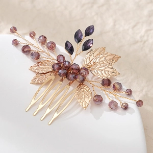 Detailed close-up of handmade bridal hair comb with gold leaves and purple beads