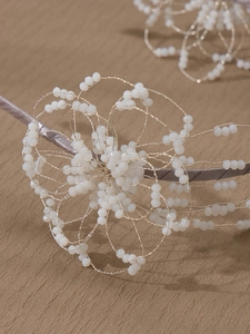 Detail of handcrafted floral headband with golden wire weaving and white beads