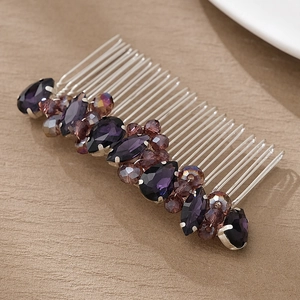 Close-up of handmade bridal hair comb with purple crystals and silver tines on wood