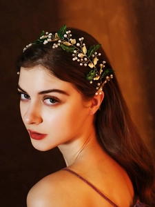 Détail du bandeau de mariée avec feuilles dorées, perles et touches vertes