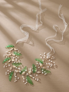 Détails d'un serre-tête de mariée fait main avec feuilles en résine verte et perles