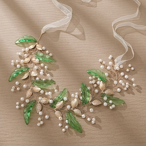 Détail de bandeau de mariée avec feuilles de résine vertes, feuillage doré et perles