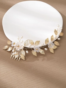 Detail of bridal hair comb with golden leaves, white resin flowers and faux pearls