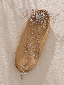 Detailed macro view of golden bridal hair comb with elegant crystals and long tassels