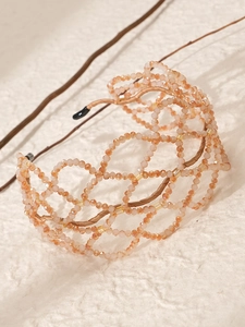 Close-up of handmade champagne crystal beaded mesh bridal headband on white background