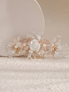 Détail d'un peigne à cheveux de mariée avec fleurs blanches et perles sur monture dorée