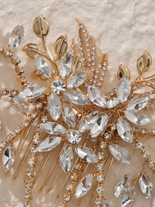 Close-up of golden bridal hair comb featuring intricate leaf designs and crystal tassels