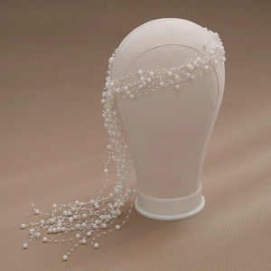 Detailed macro view of handcrafted long pearl tassel headband for weddings on a model stand