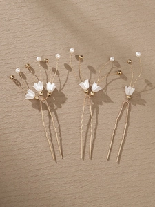 Detail of three handmade lily of the valley pearl hair pins on a textured wood background