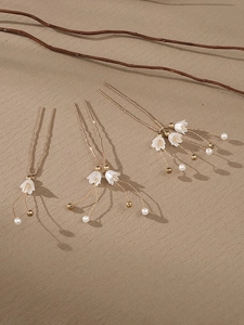 Detailed view of handmade bridal hair pins with white pearls and gold flower accents