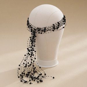 Close-up of handmade black beaded tassel headband showing layered resin beads on a white mannequin