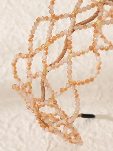 Detailed macro view of orange pink faceted crystals in a golden woven headband
