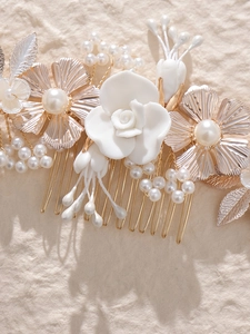 Détail d'un peigne à cheveux mariée avec roses blanches, pétales dorés et perles d'imitation