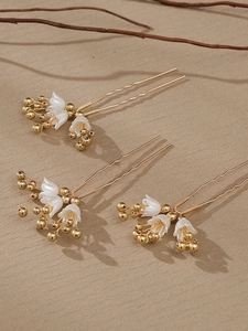 Detail of three handmade pearl flower U-shaped hair pins with gold wire and petals