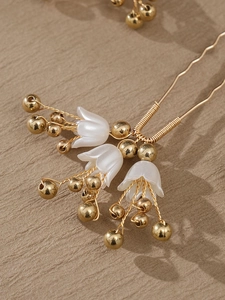 Macro shot of lily of the valley hair pin with gold beads and white frosted flower buds