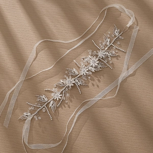 Elegant bridal hairband with handmade pearls and marquise rhinestones on warm textured background