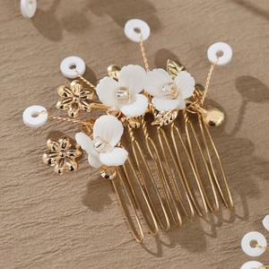 Detailed close-up of handmade gold floral hair comb with white petals and pearls