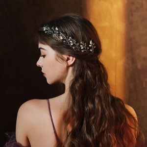 Detail of vintage bridal hair pin with pearls and green gems on an elegant model