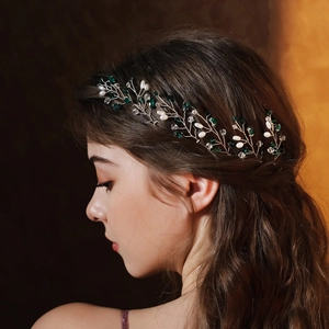Detailed side view of handcrafted bridal hair vine with green crystals and pearls