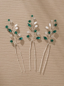 Detail of handcrafted bridal hair pins with green crystals and pearls on silver wire stems