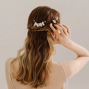 Detailed view of white floral bridal hair pins and gold combs on braided hair