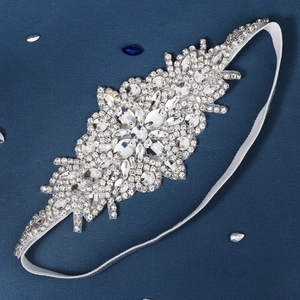 Détail macro du motif floral en strass étincelants sur un bandeau de mariée blanc souple