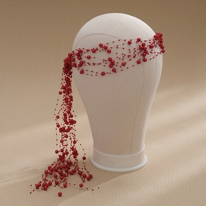Detail shot of elegant red beaded bridal headband with tassels on a white mannequin head