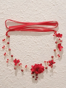 Détail de fleurs en tissu rouge et perles de cristal sur un bandeau de mariée fait main