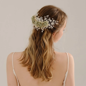 Detail of sage green floral hair clip with white pearls and crystals on bridal hairstyle